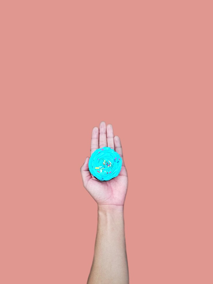 Foto primer plano de una mano humana sosteniendo un pastel contra un fondo de colores