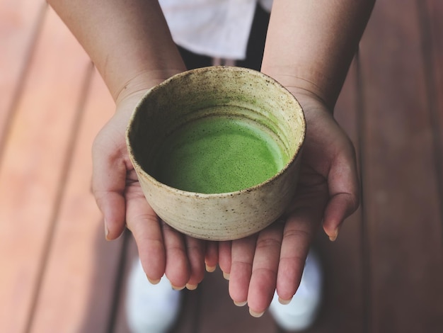 Primer plano de una mano humana sosteniendo el té