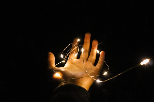 Foto primer plano de la mano iluminada sobre un fondo negro