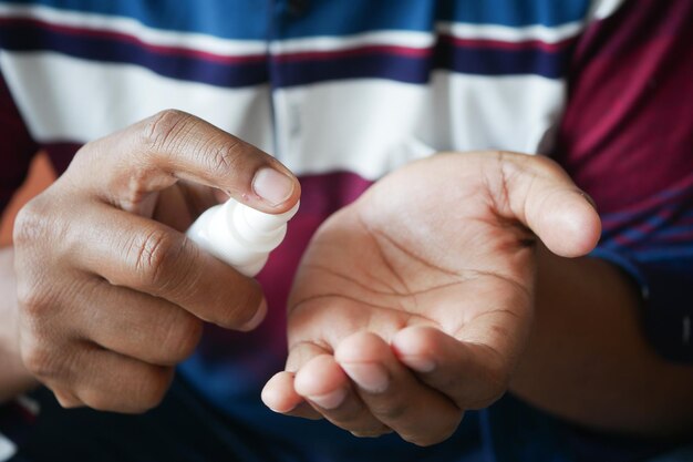 Un primer plano de la mano de un joven usando un spray de desinfectante para manos