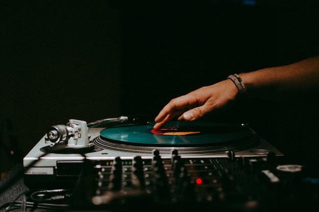 Foto primer plano de la mano jugando al tocadiscos en el cuarto oscuro