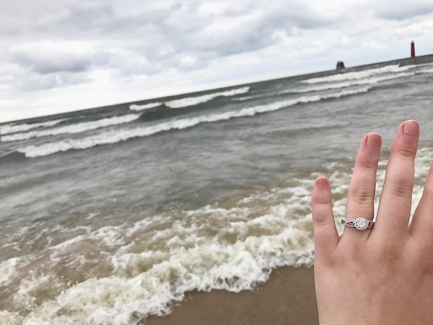 Foto primer plano de la mano en el mar contra el cielo