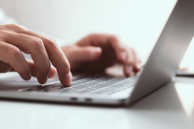 Primer plano de mano masculina escribiendo el teclado del ordenador portátil.