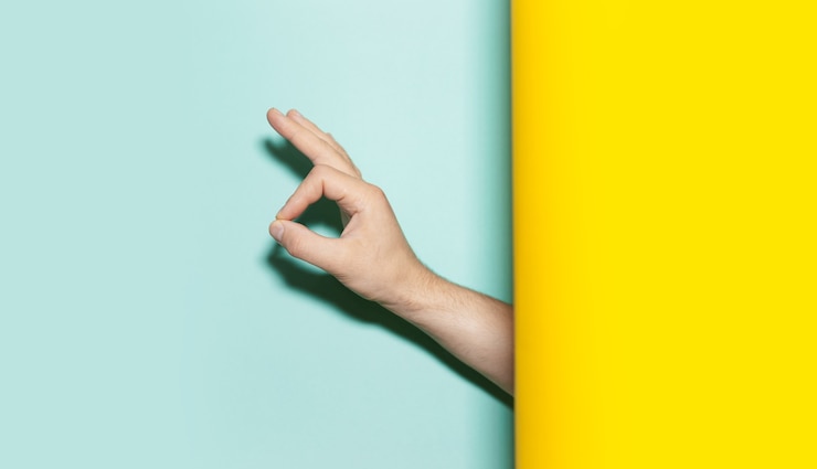 Foto primer plano de la mano masculina que muestra un gesto bien en dos colores de fondo amarillo y aqua menthe.