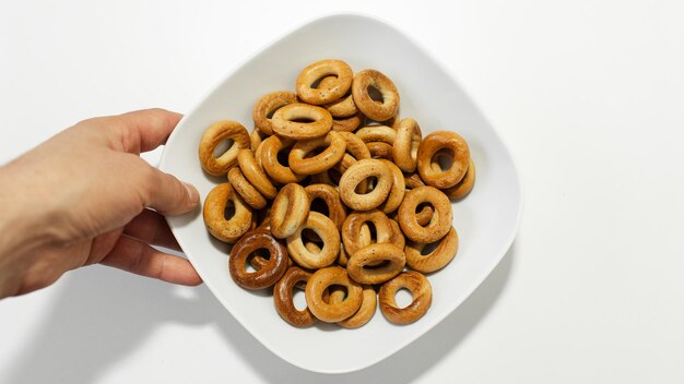 Primer plano de una mano masculina sosteniendo un plato blanco con panecillos pequeños