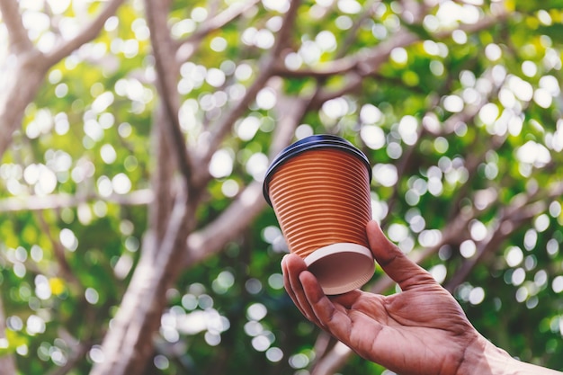 Primer plano de mano masculina sosteniendo una taza de café de papel para llevar.