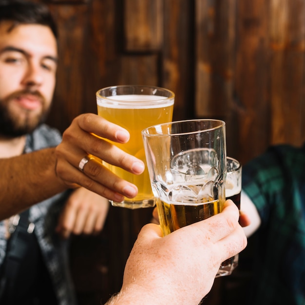 Primer plano de mano masculina tostado vasos de bebidas alcohólicas