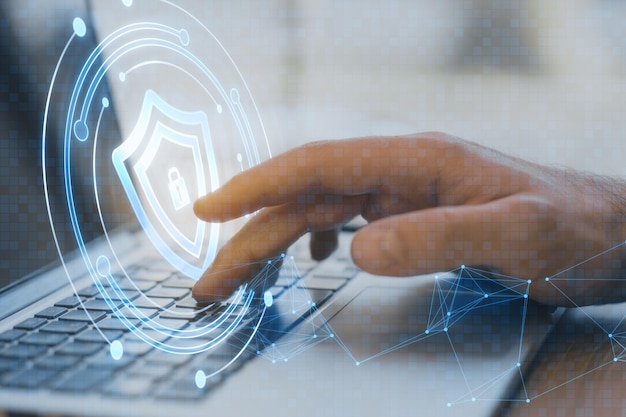 Primer plano de la mano masculina usando el teclado de la computadora portátil con holograma de seguridad redonda creativa con malla poligonal en fondo borroso concepto de aplicación de protección digital antivirus segura