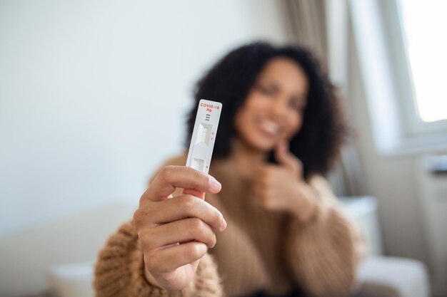 Primer plano de la mano de una mujer afroamericana sosteniendo un dispositivo de prueba negativo Mujer joven feliz que muestra su prueba rápida negativa de Coronavirus Covid19 El foco está en la pruebaCoronavirus