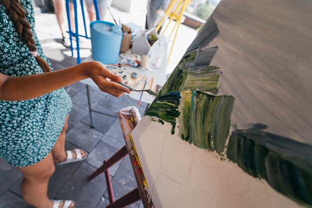 Primer plano de la mano de una mujer aplicando pintura a un lienzo