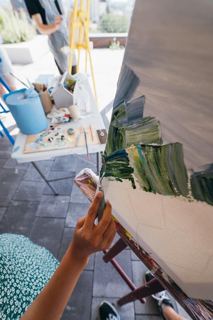 Primer plano de la mano de una mujer aplicando pintura a un lienzo