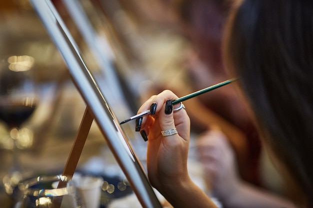 Primer plano de una mano de una mujer artista pintando un cuadro