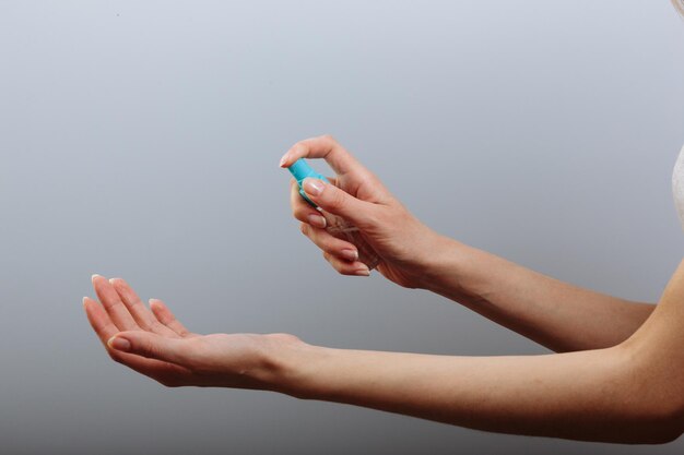 Primer plano de la mano de una mujer bonita haciendo alcohol en aerosol para esterilizar el virus.