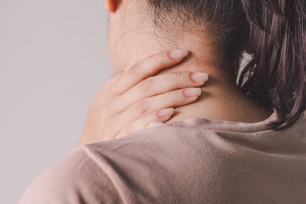 Primer plano de la mano de la mujer en el cuello contra un fondo beige