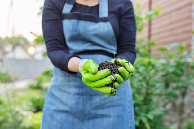 Foto primer plano de la mano de una mujer en guantes de jardinería con suelo fértil negro