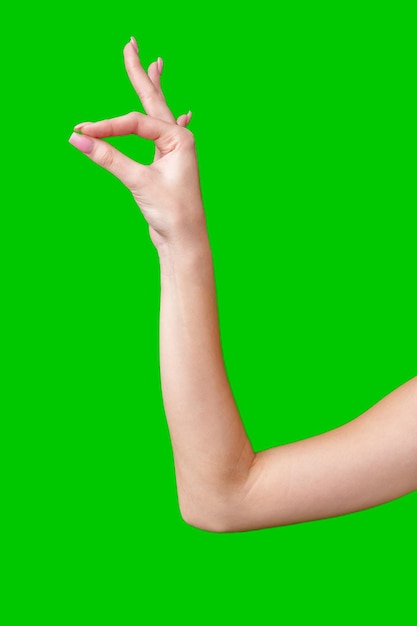 Un primer plano de la mano de una mujer haciendo la señal de OK contra una pantalla verde