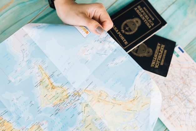 Foto primer plano de la mano de una mujer con mapa y pasaportes