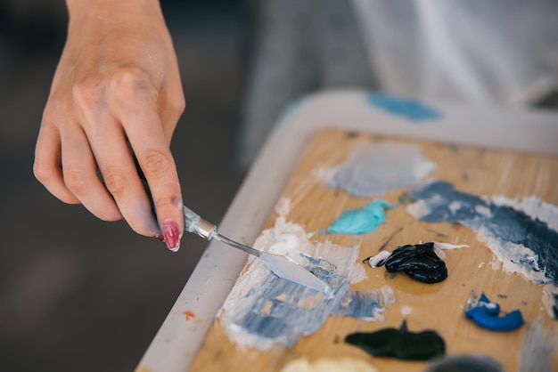 Primer plano de la mano de la mujer mezclar pinturas en la paleta