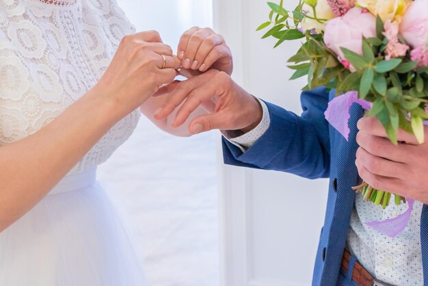 Primer plano en la mano de una mujer que se puso un anillo de compromiso en el dedo del novio matrimonio de conveniencia ceremonia de boda al aire libre la pareja intercambia los anillos de boda recién casados