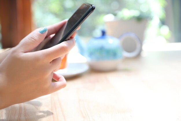 Primer plano de la mano de la mujer que sostiene el comercio de acciones y datos de teléfonos inteligentes en el concepto de negocio de fondo de la cafetería