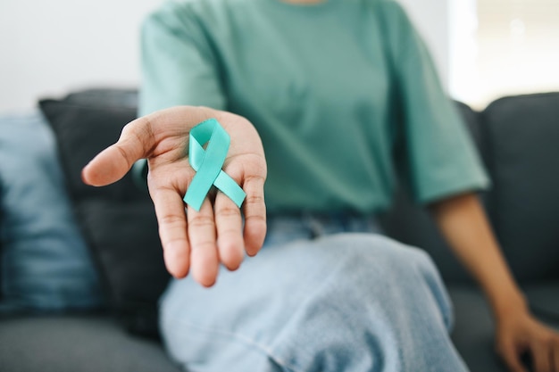 Primer plano de la mano de una mujer sosteniendo una cinta de concienciación azul para apoyar a un sobreviviente de cáncer