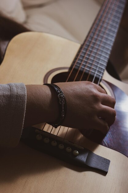 Primer plano de la mano de una mujer tocando un acorde en una guitarra acústica