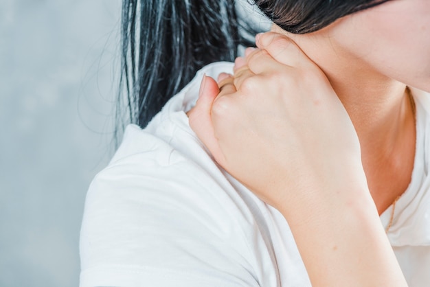 Primer plano de la mano de una mujer tocando su cuello