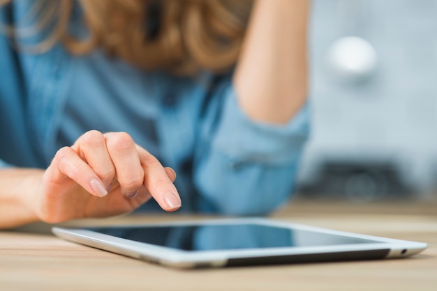 Foto primer plano de la mano de la mujer tocando la tableta digital con el dedo