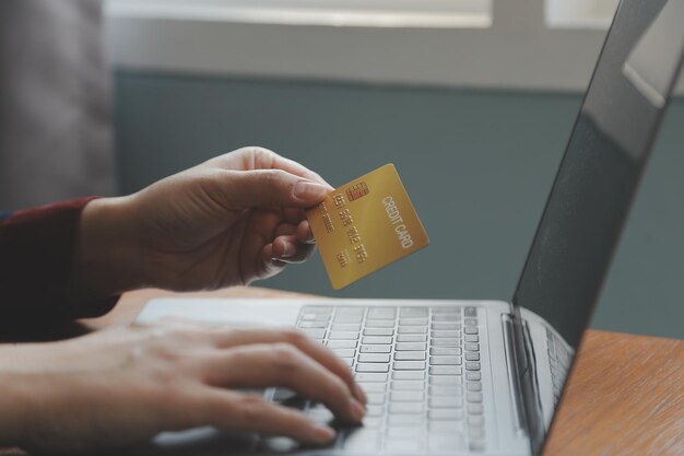 Primer plano de la mano de la mujer usando tarjeta de crédito y computadora portátil para pagos y compras en línea Pagos de compras en línea banca digital Concepto de comercio electrónico