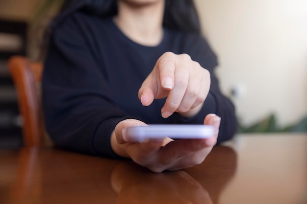 Foto primer plano de la mano de una mujer usando un teléfono móvil