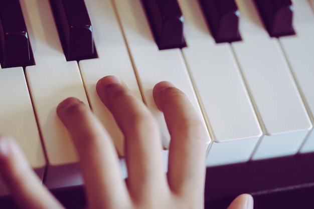 Primer plano de una mano musical para niños tocando el piano.