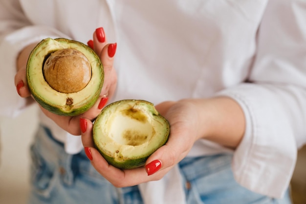 Primer plano de la mano de una niña sosteniendo un aguacate cortado en dos