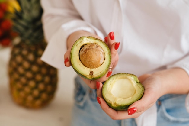 Primer plano de la mano de una niña sosteniendo un aguacate cortado en dos