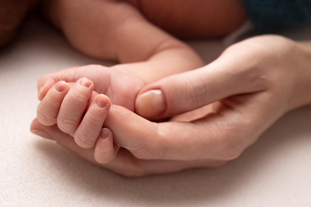 Primer plano de la mano del niño y la palma de la madre y el padre El bebé recién nacido tiene un agarre firme en el dedo de los padres después del nacimiento Un recién nacido se aferra al dedo de mamá y papá