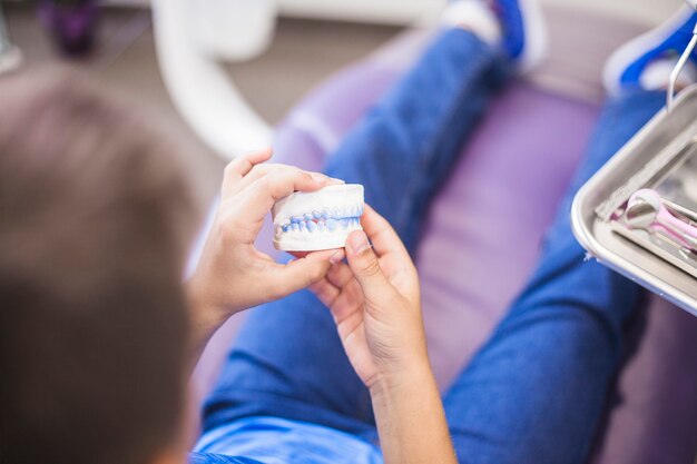 Primer plano de la mano de un niño sosteniendo los dientes molde de yeso