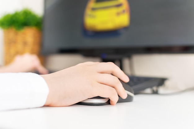 Foto el primer plano de la mano del niño sostiene un mouse de computadora y presiona los botones el niño está jugando un videojuego en casa