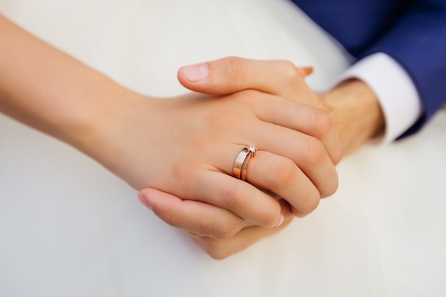 Primer plano de la mano de la novia con anillo de bodas. los recién casados están tomados de la mano.