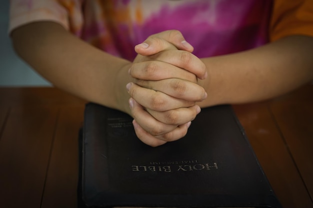 Primer plano de la mano de oración con el libro espiritual de la biblia