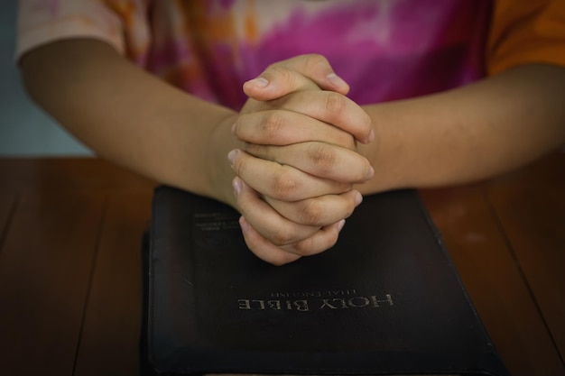 Primer plano de la mano de oración con el libro espiritual de la Biblia conceptos de oración mediante el estudio de las Sagradas Escrituras