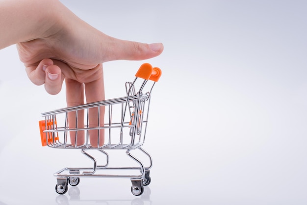 Primer plano de la mano en un pequeño carrito de compras contra un fondo blanco