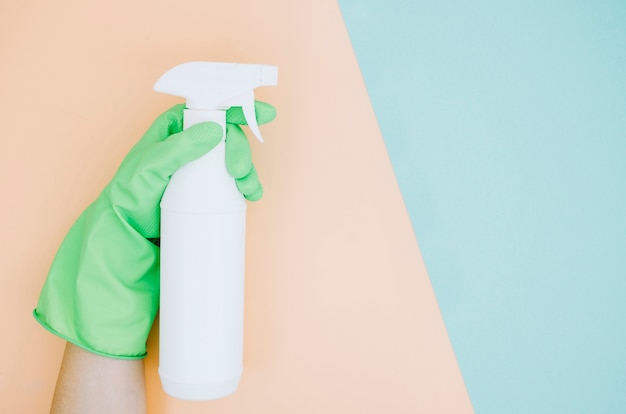 Primer plano de la mano de una persona sosteniendo una botella de spray blanco sobre doble fondo