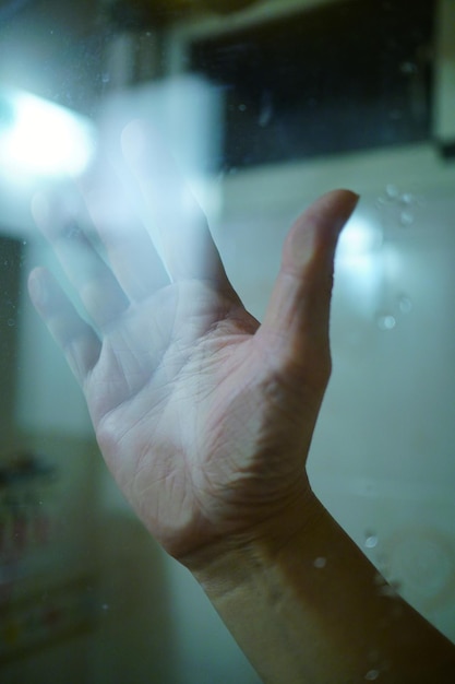 Primer plano de la mano de una persona en una ventana de vidrio