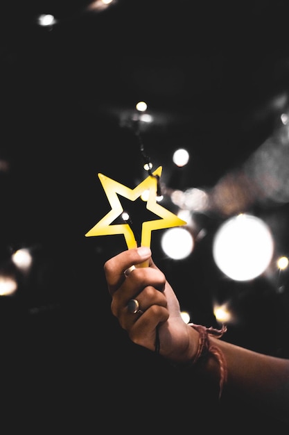 Primer plano de una mano que sostiene una decoración navideña en forma de estrella iluminada