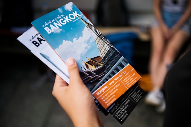 Foto primer plano de la mano que sostiene el folleto de guía de viaje de bangkok