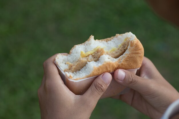 Primer plano de la mano que sostiene la hamburguesa para comer, concepto de comida