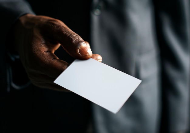 Primer plano de la mano que sostiene la tarjeta de papel blanco en blanco