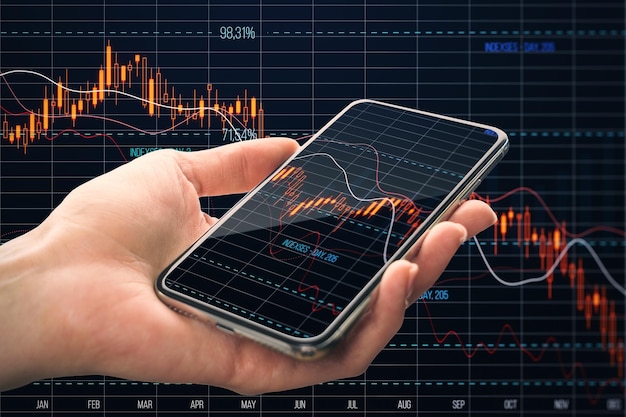 Primer plano de la mano que sostiene el teléfono inteligente con la caída del gráfico de divisas de crisis roja sobre el fondo de la cuadrícula oscura Concepto de comercio y caída de la recesión