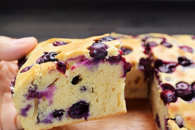 Foto un primer plano de la mano recogiendo una rebanada de un delicioso pastel de arándanos