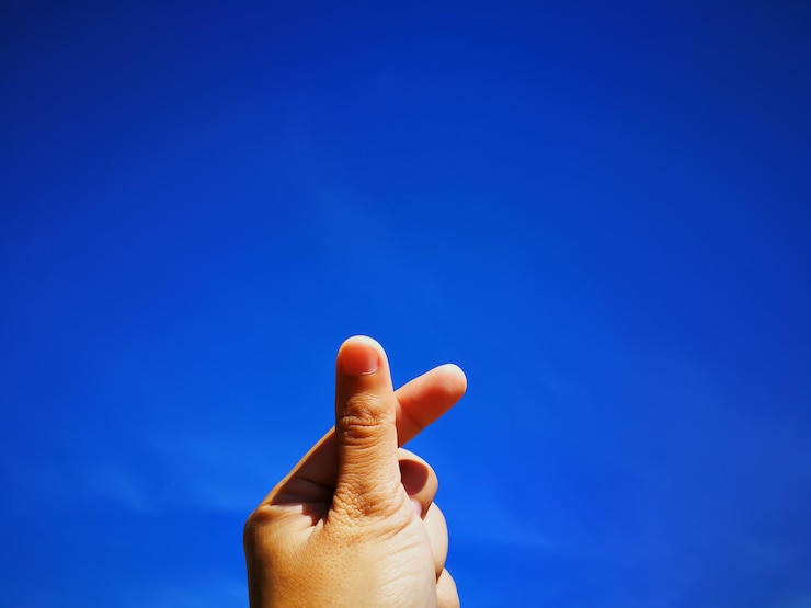 Foto primer plano de una mano recortada haciendo gestos contra el cielo azul