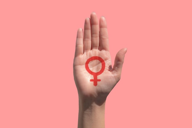 Primer plano de la mano recortada con el signo contra un fondo rosa